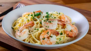 Creamy garlic shrimp linguine with juicy pink shrimp, garnished with fresh parsley and parmesan cheese, served on a rustic wooden table - final plated dish ready to eat.