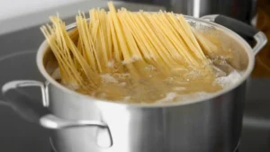 Linguine pasta being added to a pot of boiling water.