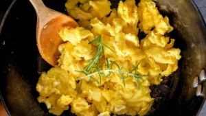 Lightly scrambled eggs cooking in a wok, forming large, soft curds.