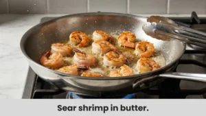 Shrimp sizzling and turning pink in butter and olive oil in a pan.