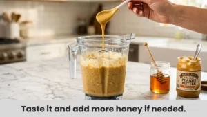 Tasting and adjusting the sweetness of a Peanut Butter Banana Smoothie by adding more honey or an extra spoonful of peanut butter.