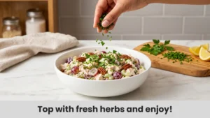 Sprinkling fresh chives and parsley over chicken salad in serving bowl for final summer garnish.