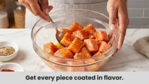 Salmon cubes being tossed in olive oil, honey, and paprika seasoning mix for air fryer salmon bites.