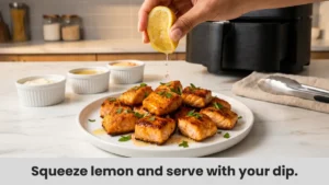 Air fryer salmon bites being served with fresh lemon juice squeeze and parsley garnish with dipping sauces.