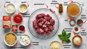 Fresh ingredients for lasagna soup with cottage cheese including ground beef, tomatoes, pasta, and cheeses on marble counter